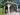 Wooden pergola with two chairs on a deck surrounded by greenery