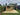 Wooden gazebo on a patio with a garden and house in the background